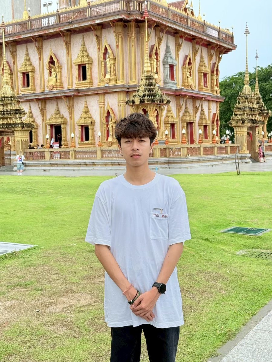 Parinya Ardhan ยืนอยู่บนสนามหญ้าหน้าวัดไทย